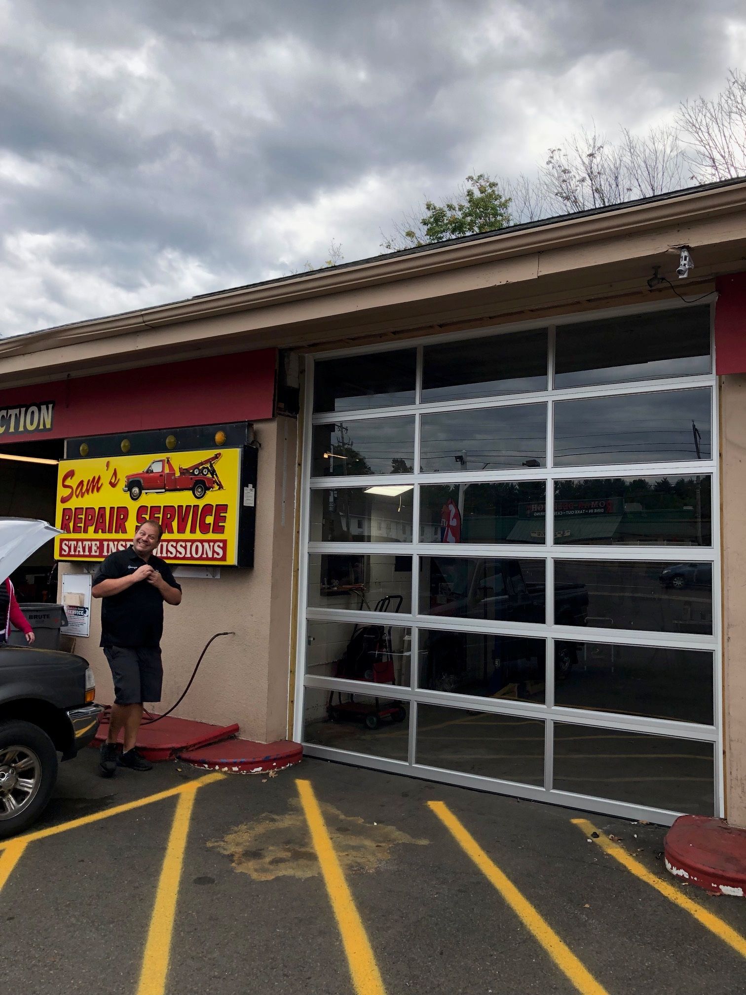 Commercial truck garage with yellow truck on a flatbed, brick accents, and a sunset sky. Commercial truck garage with yellow truck on a flatbed, brick accents, and a sunset sky.