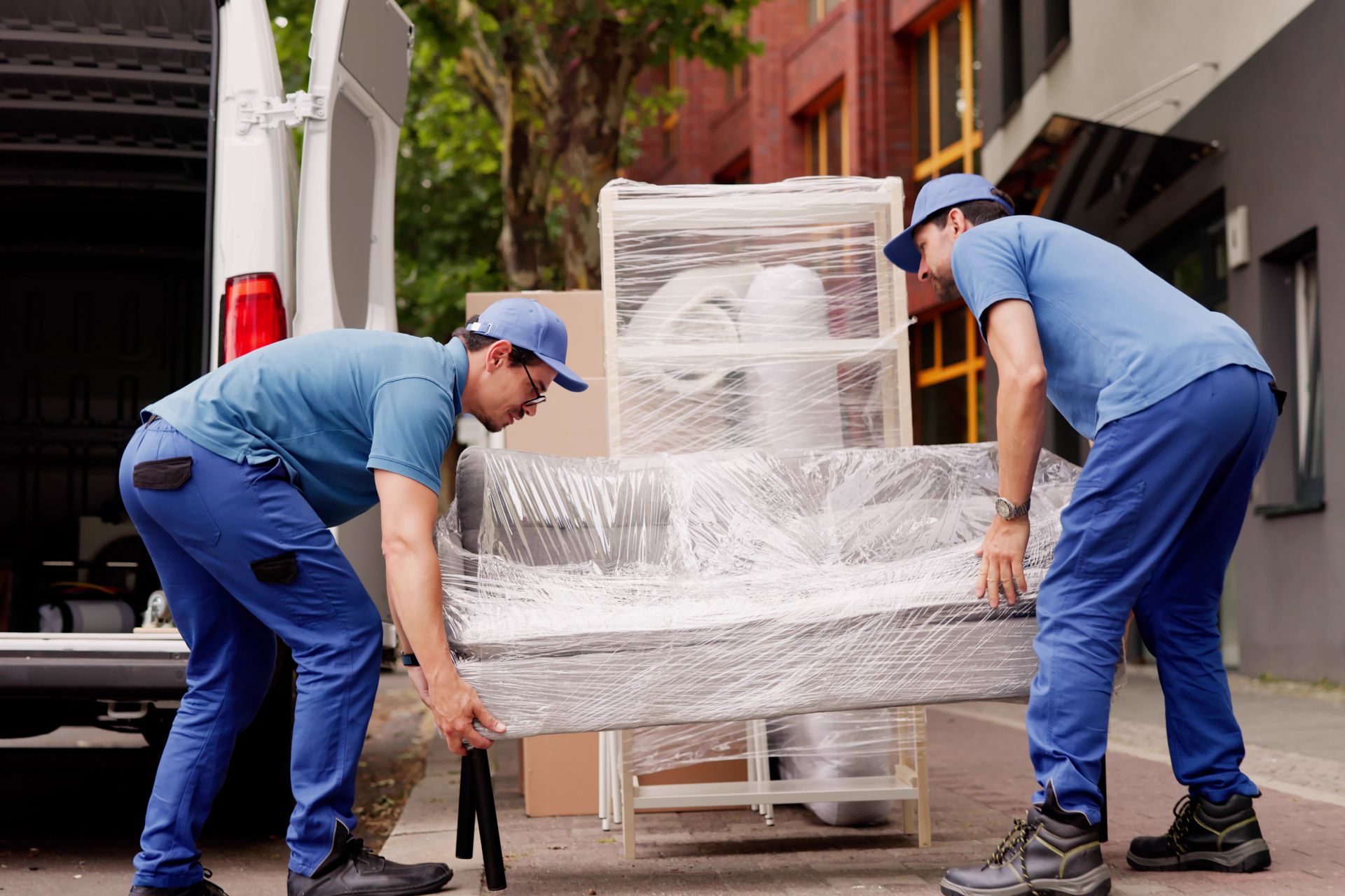 Movers loading a wrapped up couch to a truck