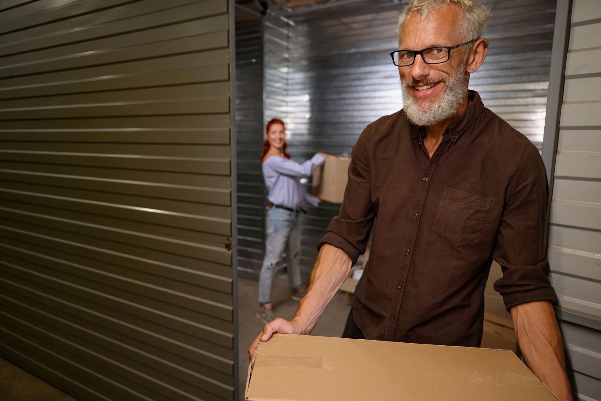 A woman is helping a man load boxes to a storage unit.