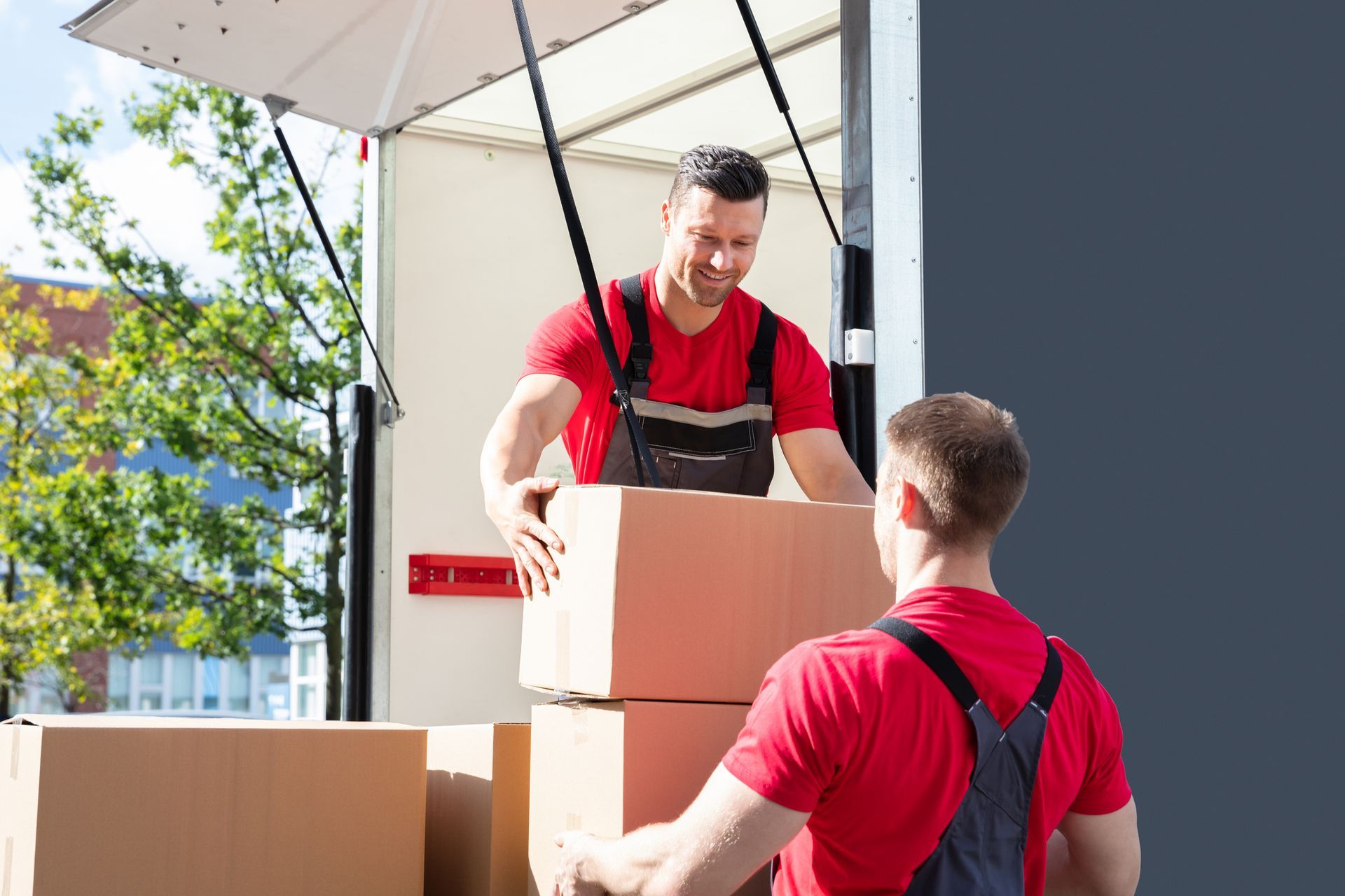 Two men unloading boxes from a moving truck, showcasing full-service movers in action.