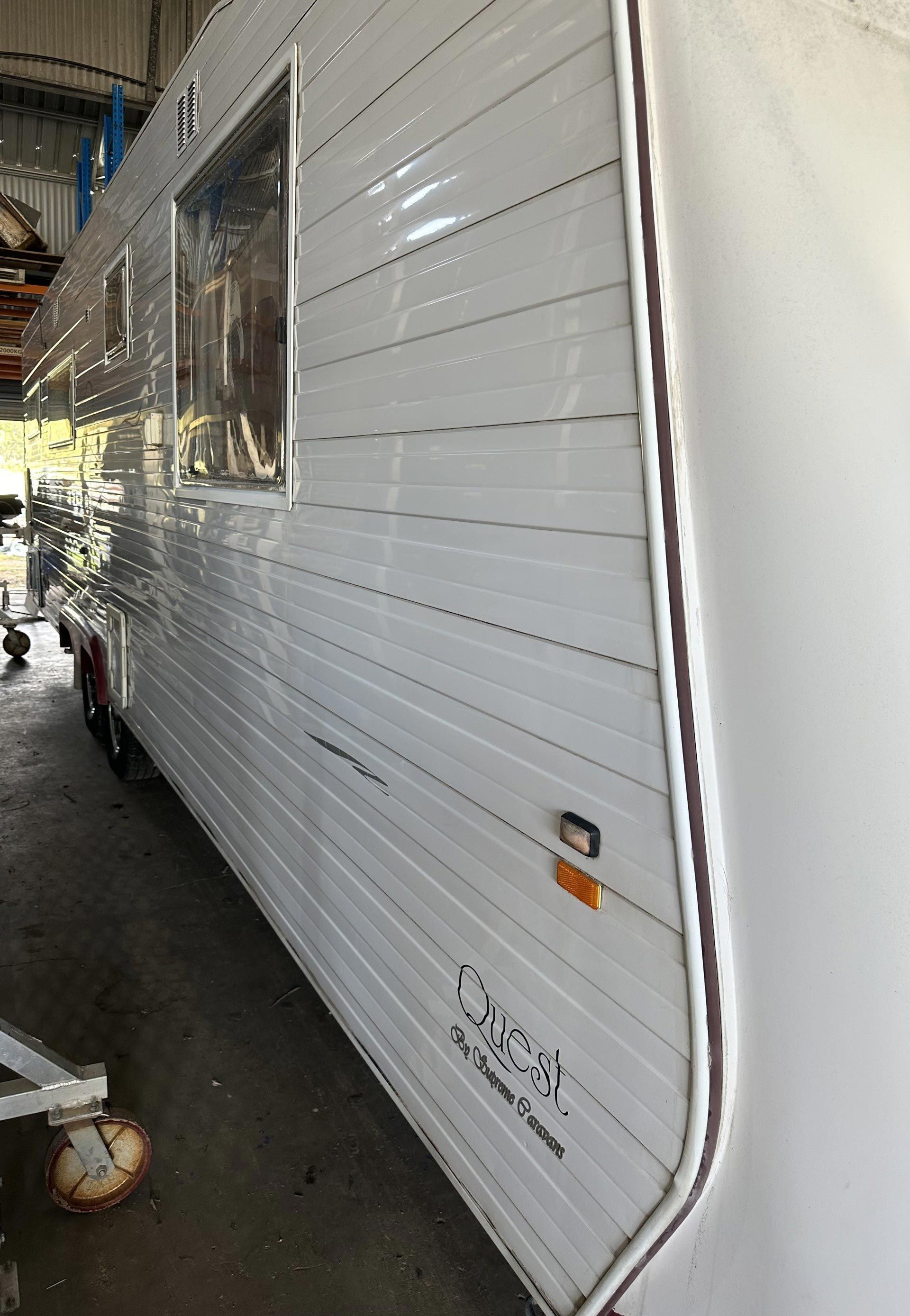 White trailer side in a covered area, with a curved trim edge and a small amber reflector near the bottom