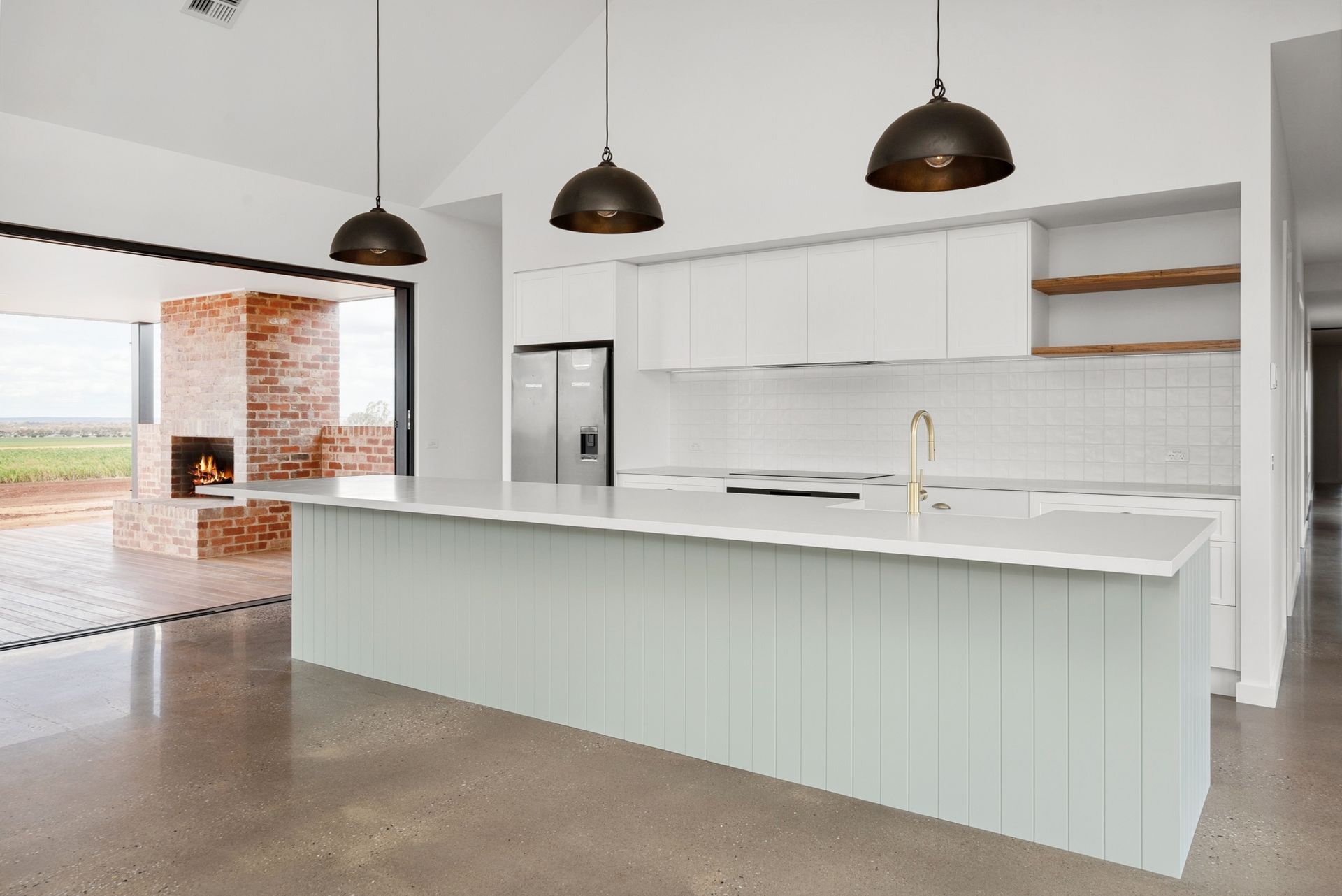 An empty kitchen with white cabinets and a large island.