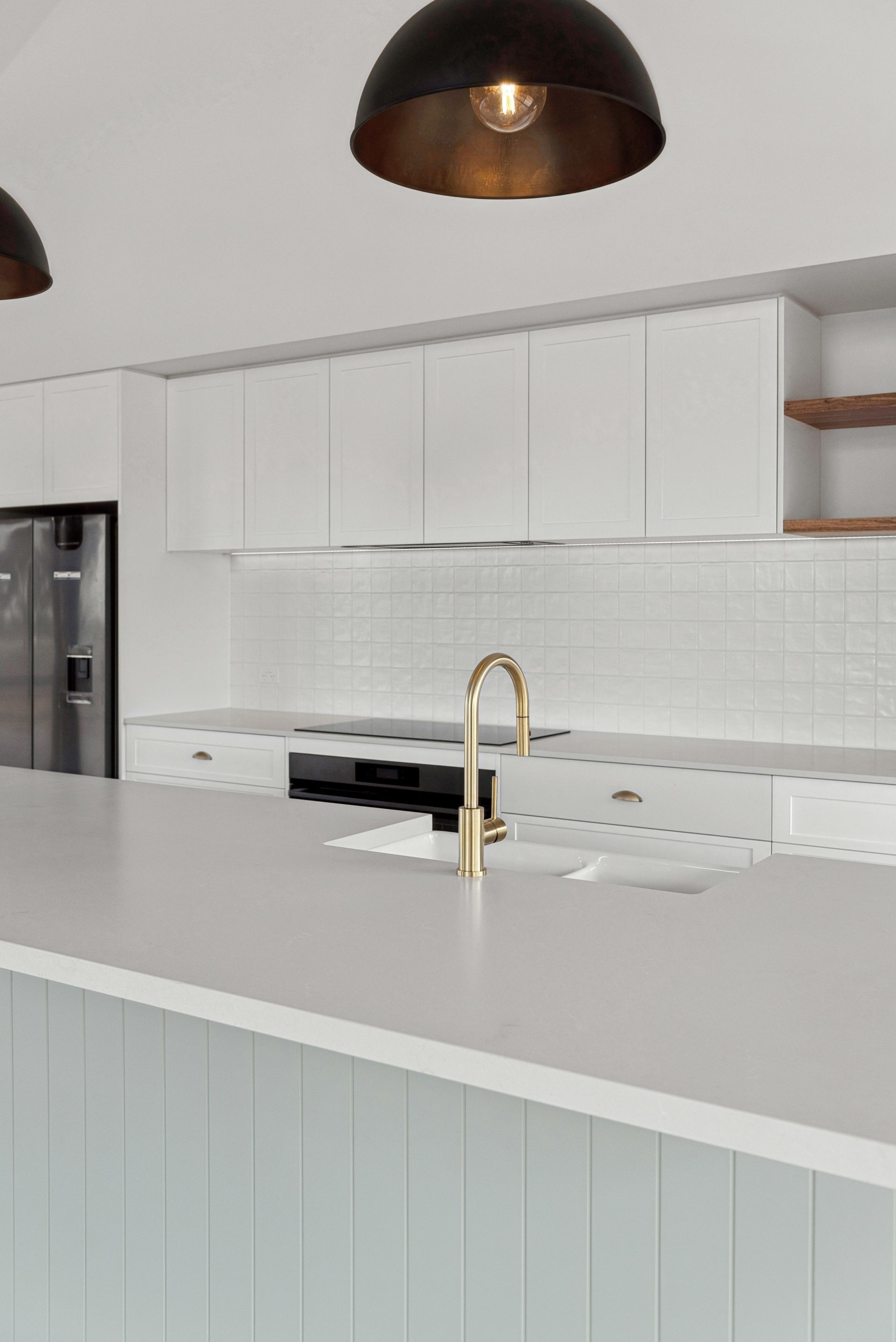 A kitchen with white cabinets , a sink , and a refrigerator.