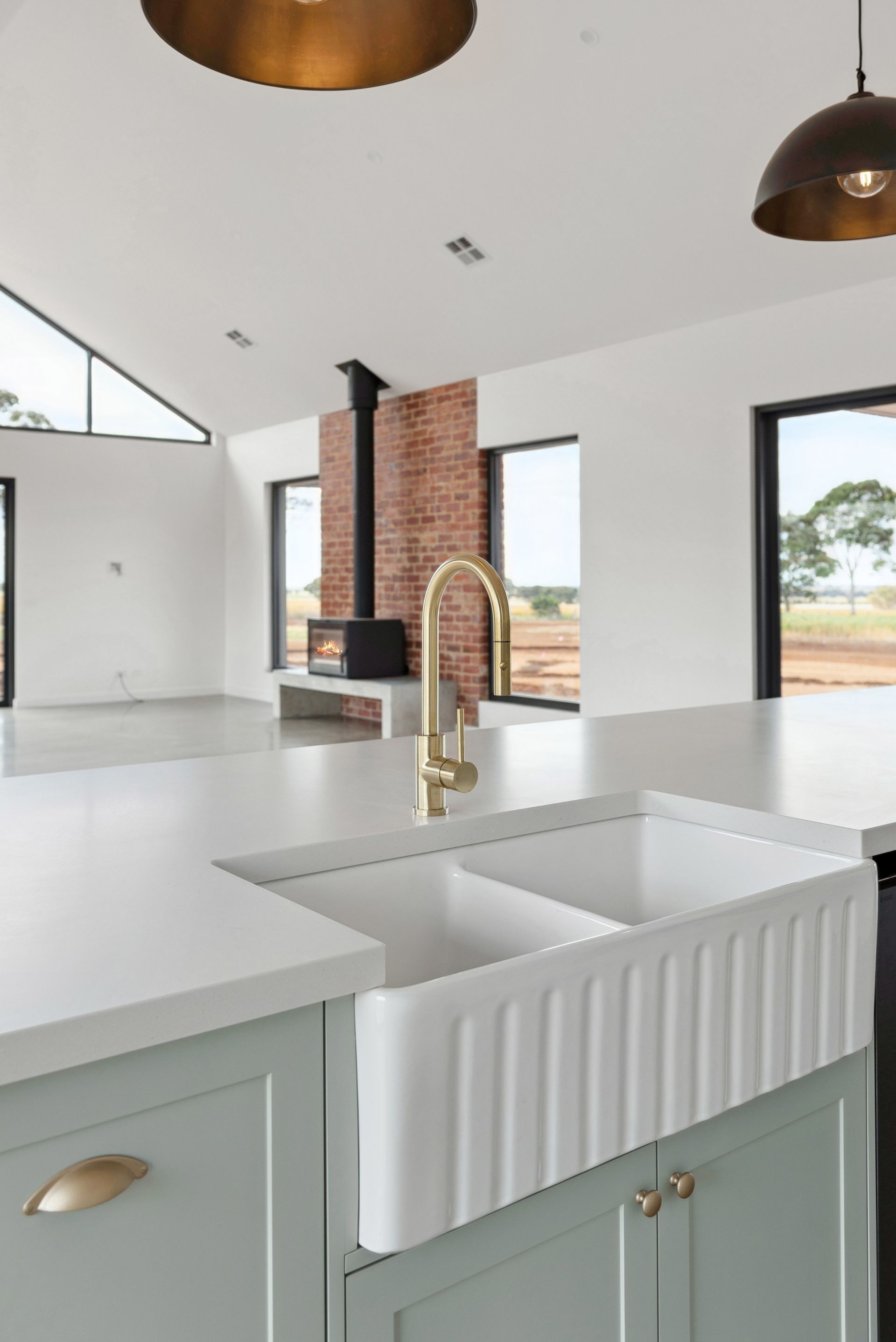 A kitchen with two sinks and a brass faucet