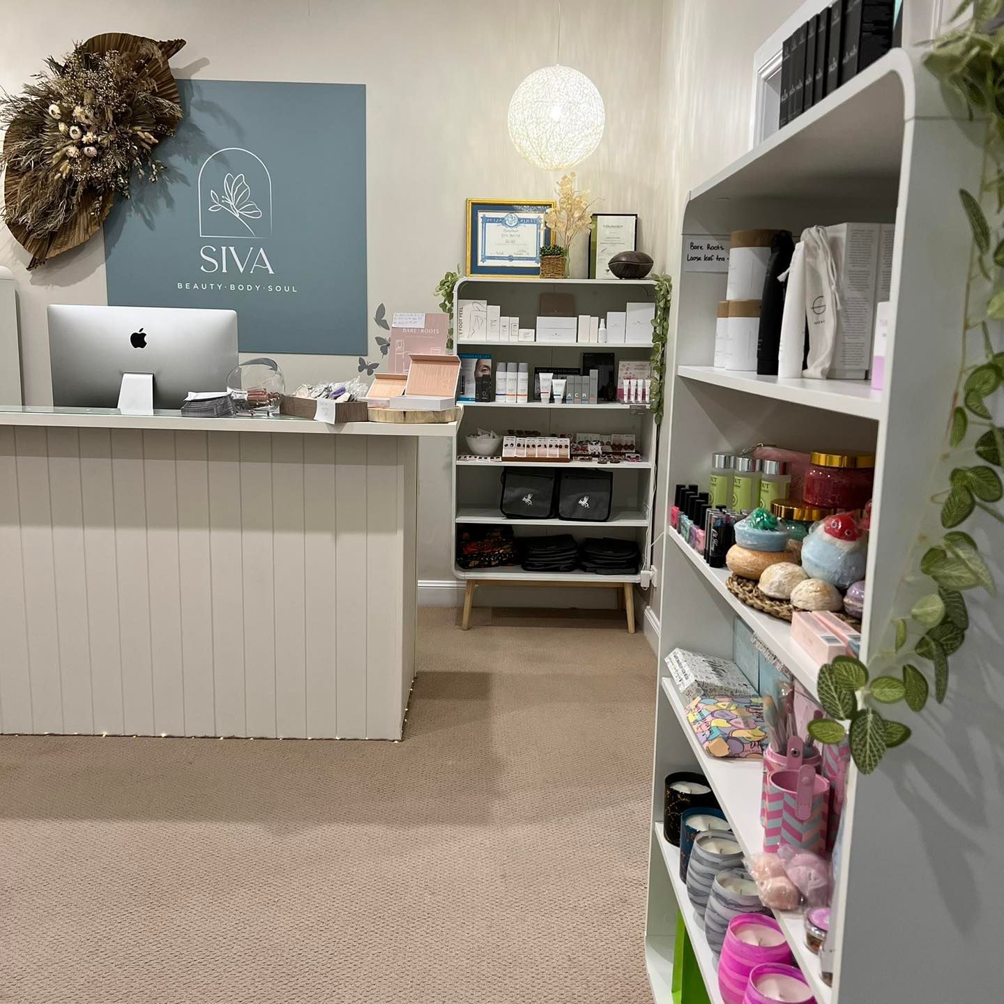 Interior shop with white shelves displaying products, a counter with a computer, and a sign.
