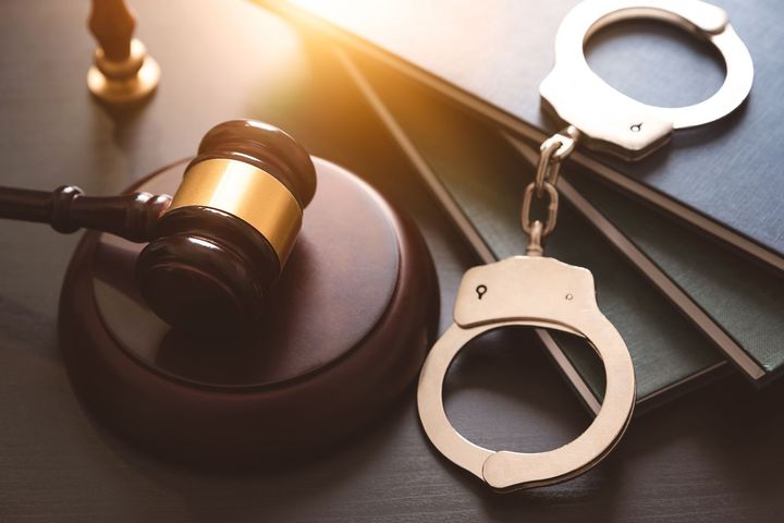 Handcuffs and Judge’s Gavel on Table