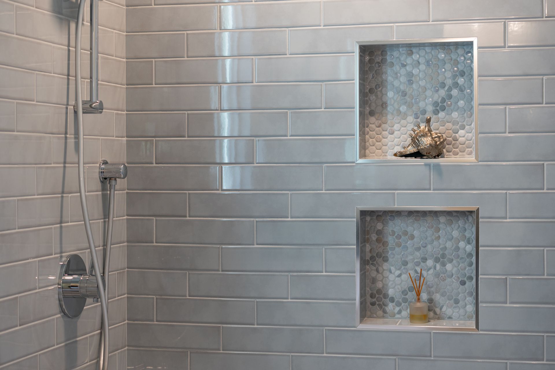 Modern bathroom with gray tile shower, decorative insets, and chrome finishes