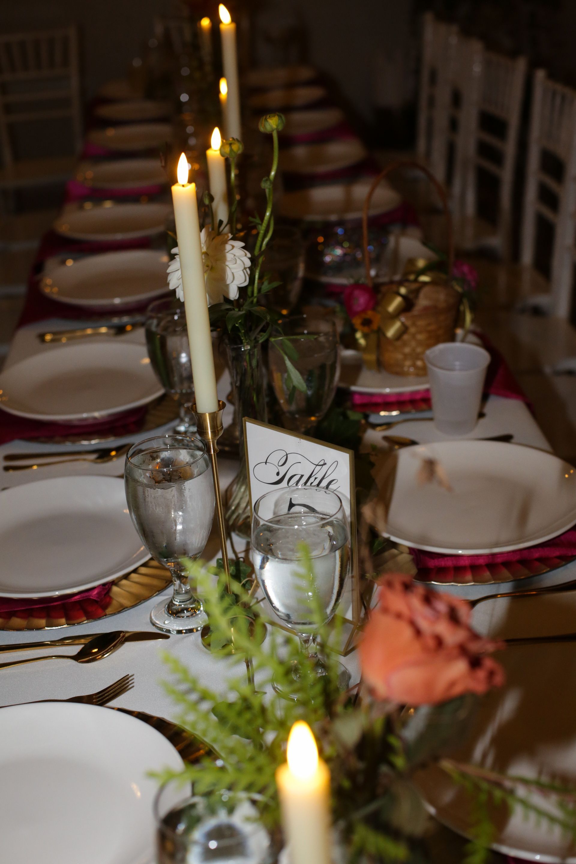 Long dining table set with candles, flowers, and place settings; overhead view.