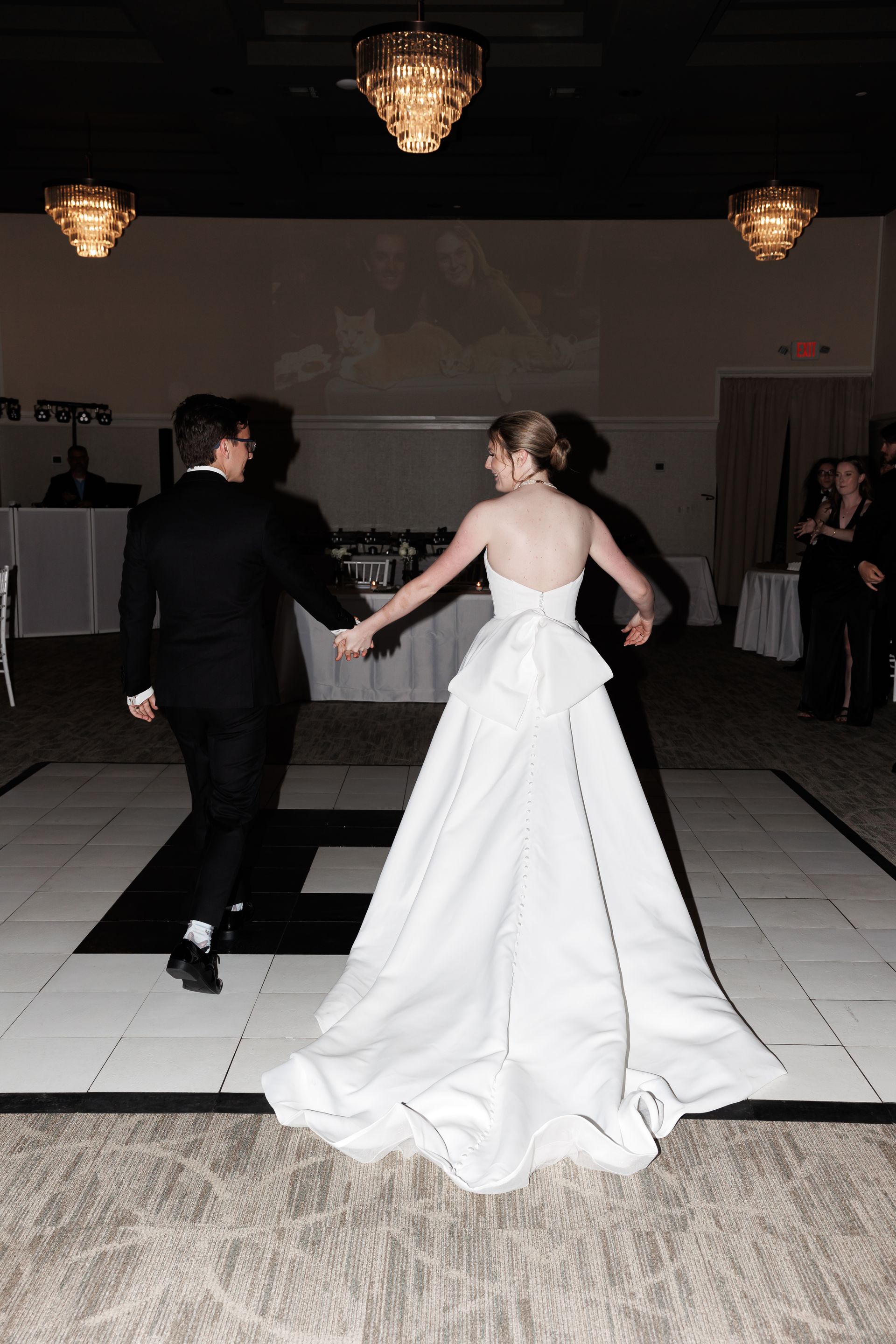 Bride and groom dance on a checkered dance floor at their wedding reception.