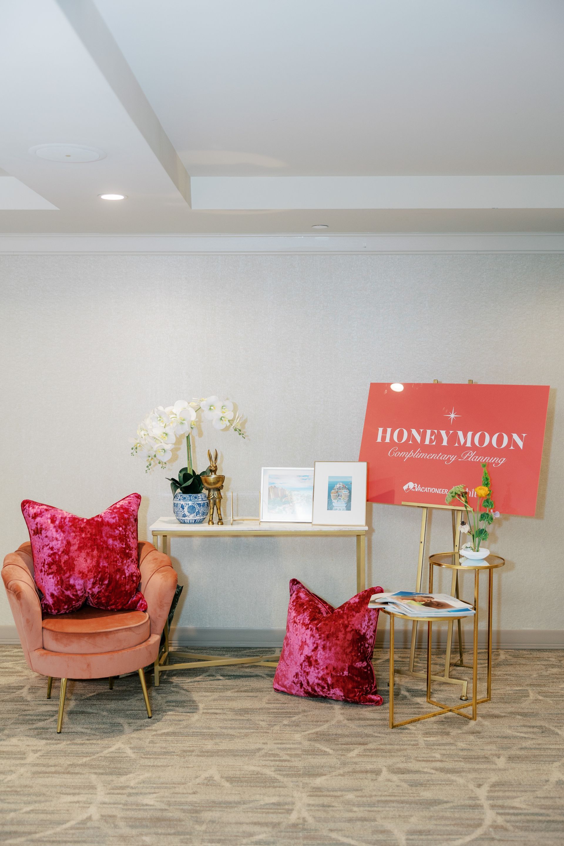 A decorated space with a pink chair, gold tables, and a red 
