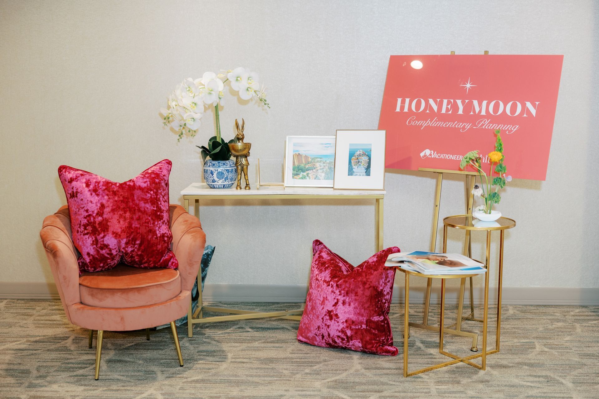 Pink chair with pillows, a table with decor, and a “Honeymoon” sign.