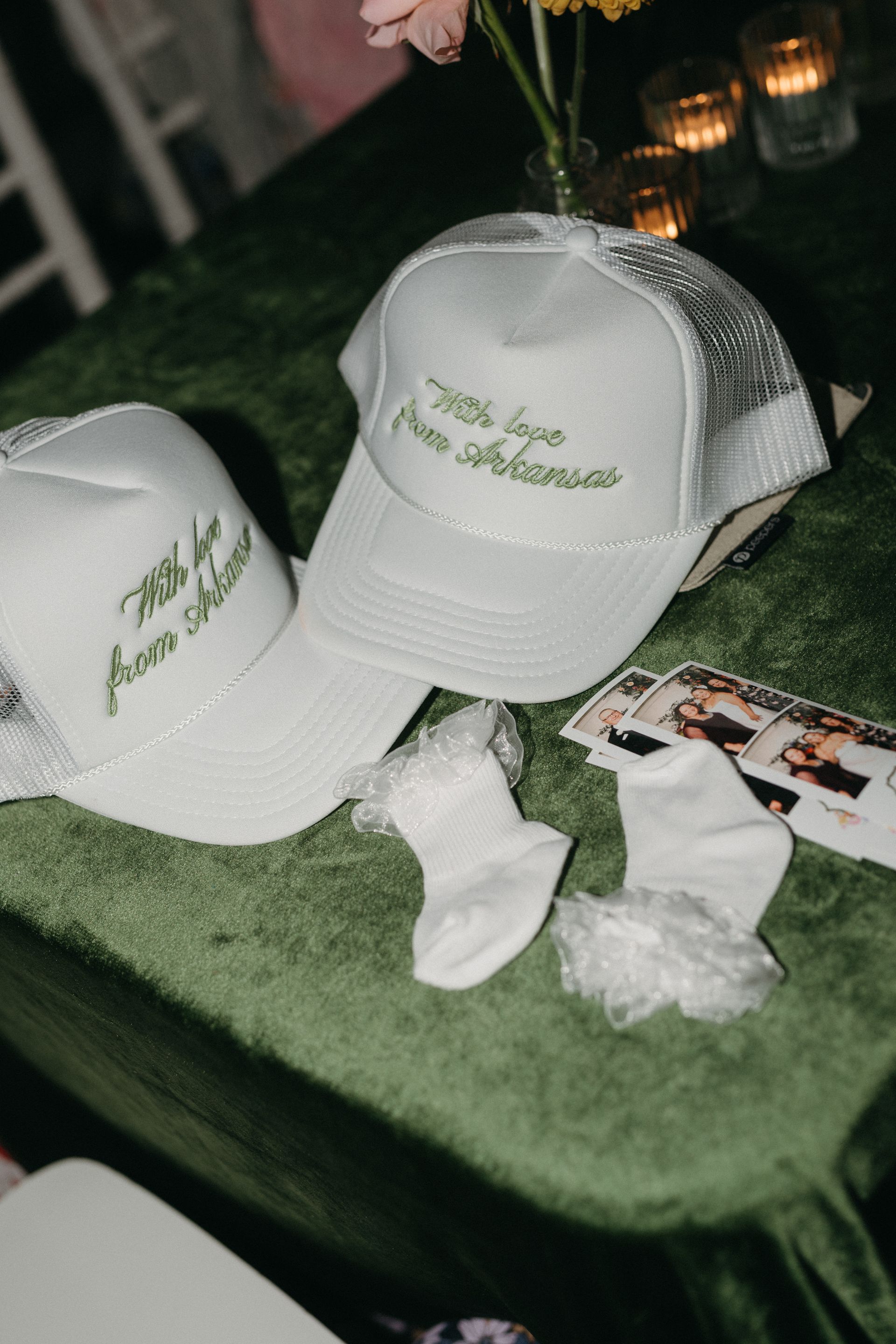 Two light green hats with white mesh and writing, small white socks on a green surface.