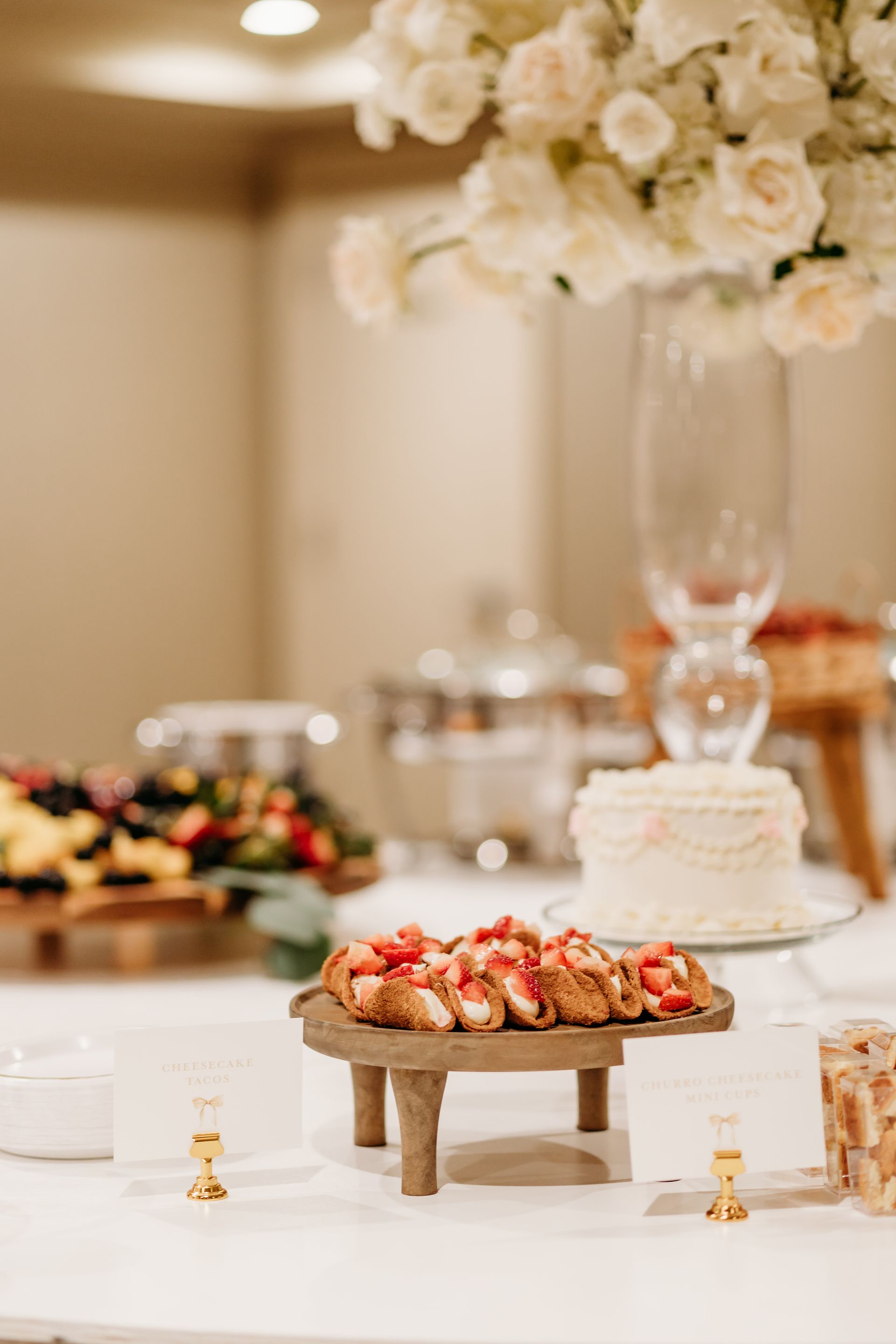 Buffet table with strawberry bruschetta, cake, flowers, and other food.