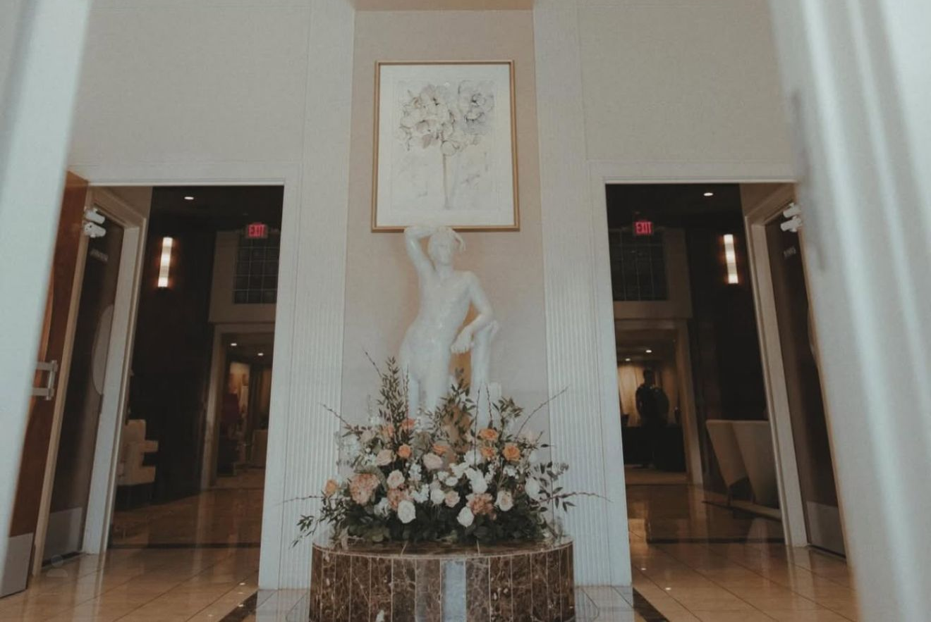 Elegant white lobby with chandelier, sculpture, and floral arrangement.