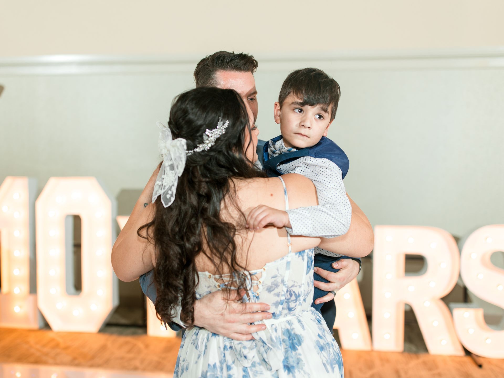 Family embraces, child in father's arms, by lighted 
