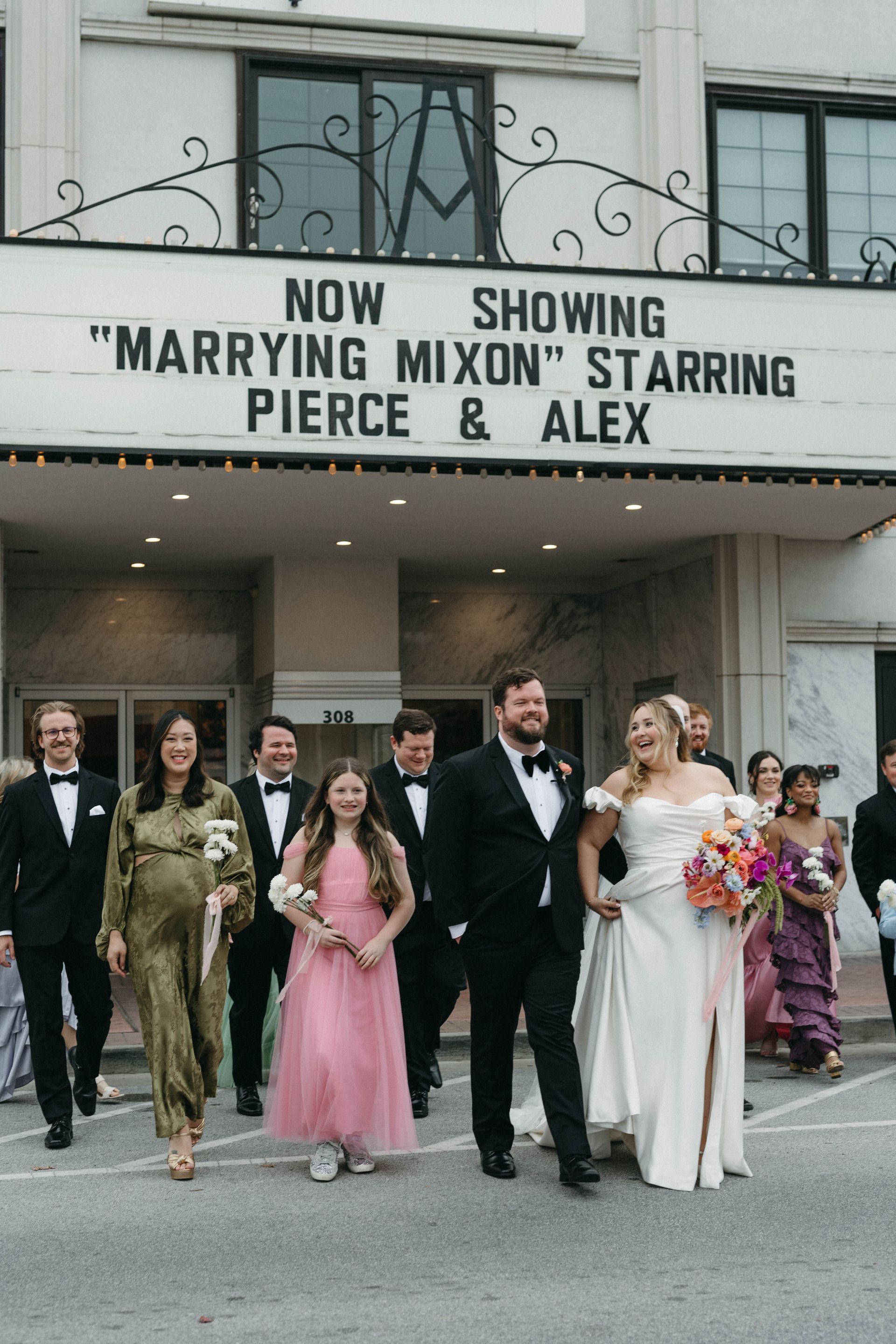 Wedding party exiting theater with marquee reading 