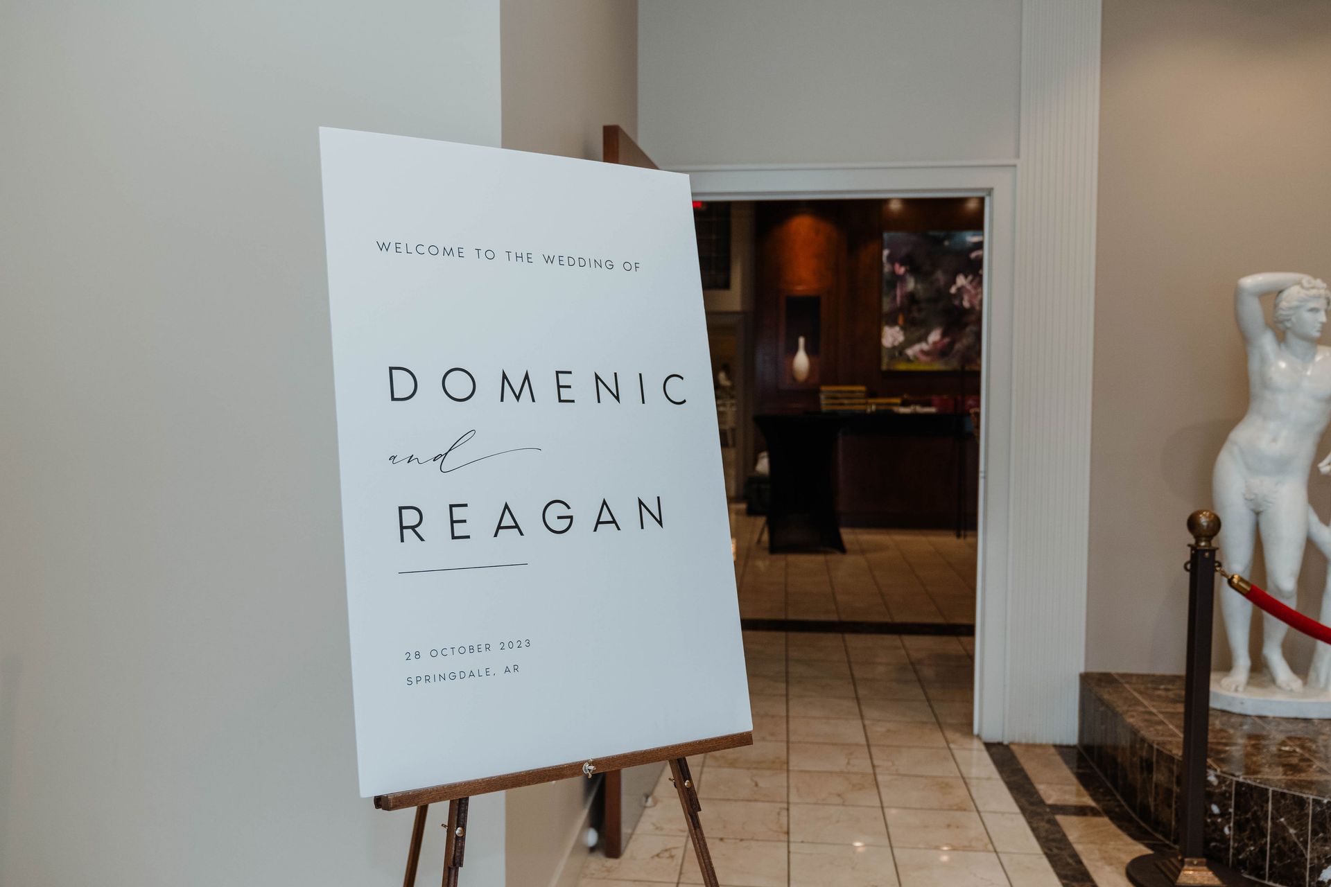 A white welcome sign on an easel in an entryway; text reads 