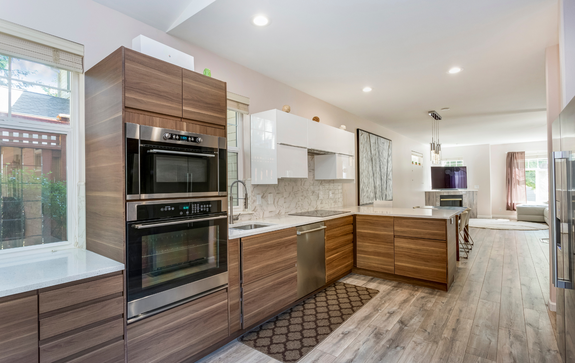 Modern kitchen with wood cabinets, stainless steel appliances, and white countertops.