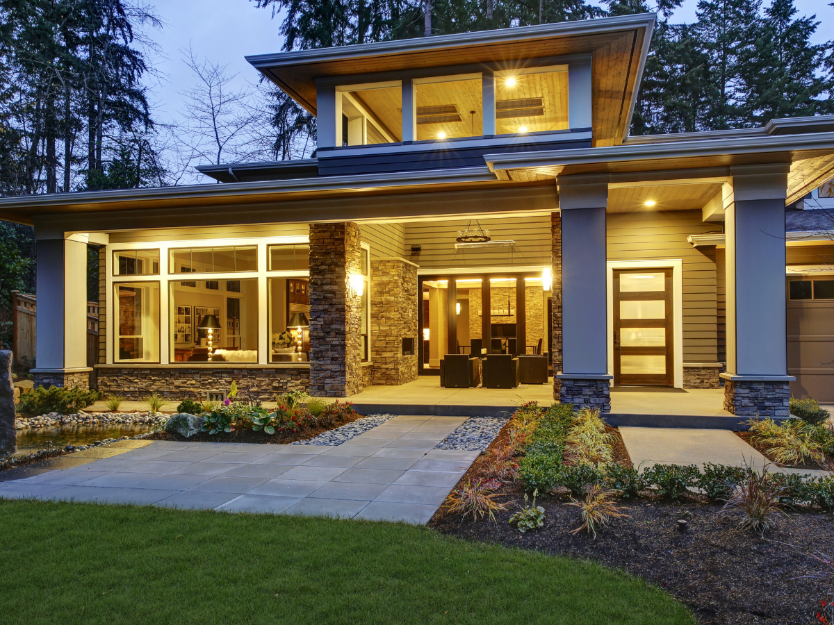 Modern home with stone accents and large windows; evening setting.