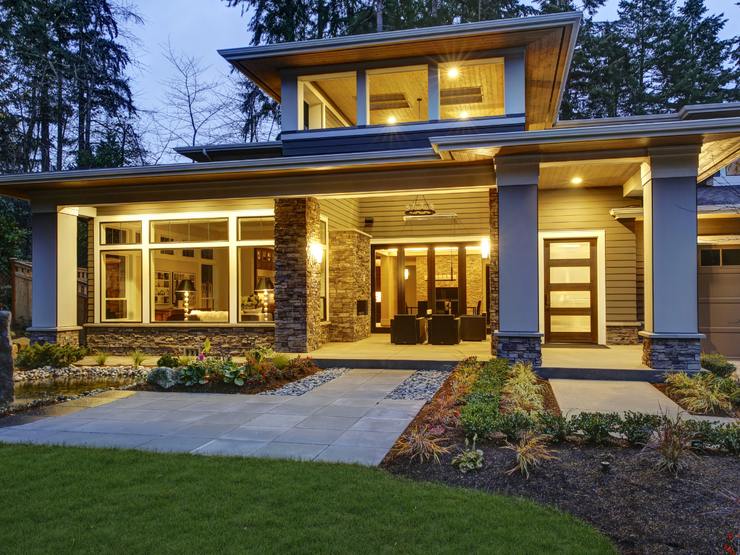 Modern home with stone accents and large windows; evening setting.