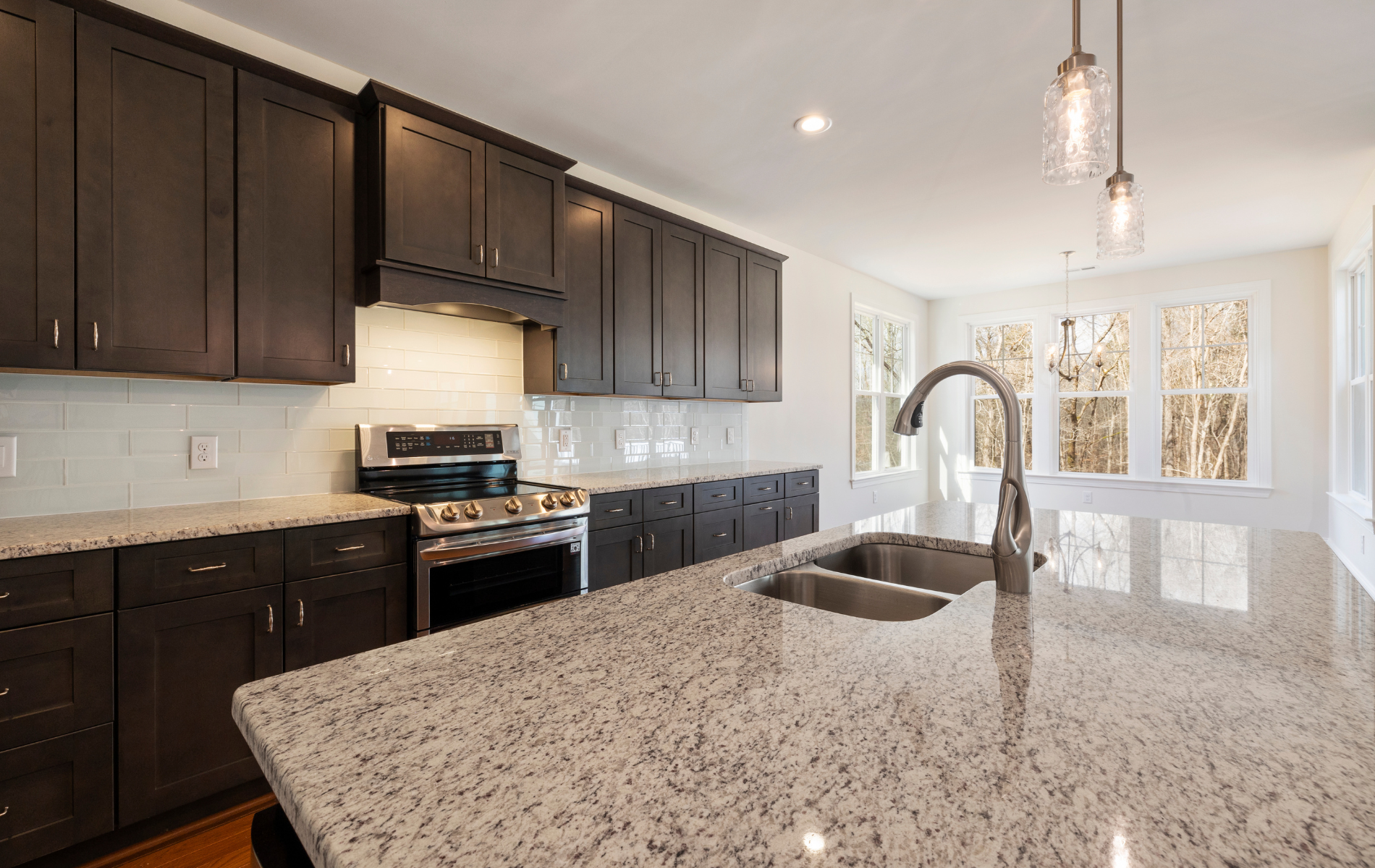 Modern kitchen with dark brown cabinets, granite countertops, and a stainless steel sink and faucet.