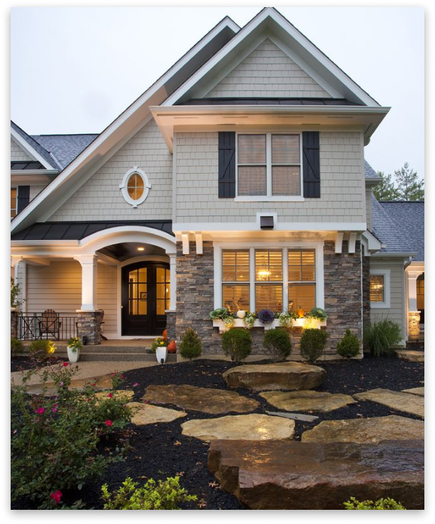 Two-story house with stone and beige siding, black shutters, and a flagstone pathway.