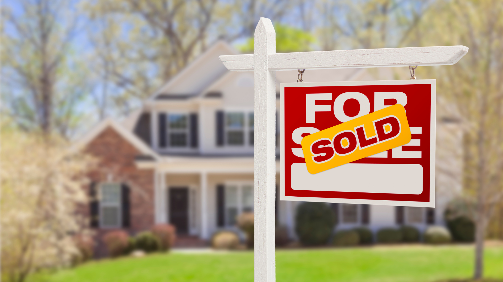 A for sale sign is hanging in front of a house.