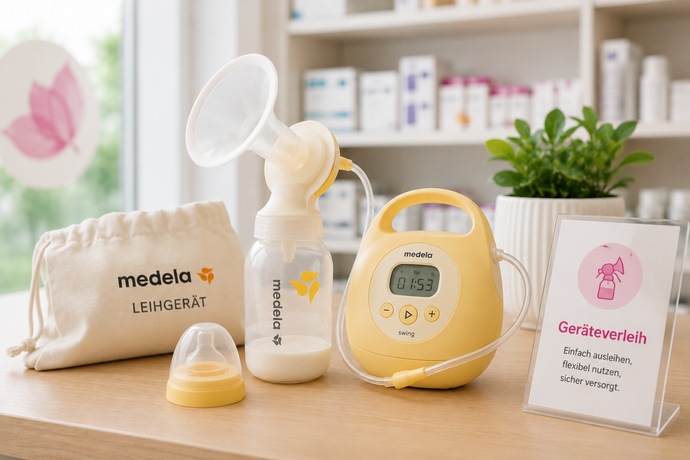 Brustpumpe und Medela-Flaschen auf einem Holztisch neben einer rosa Karte und einer Topfpflanze