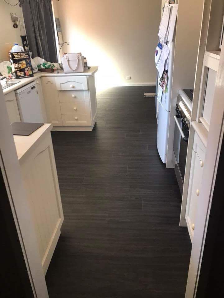 A Kitchen With A Black Floor And White Cabinets And Appliances — Queanbeyan Carpets in Queanbeyan, NSW