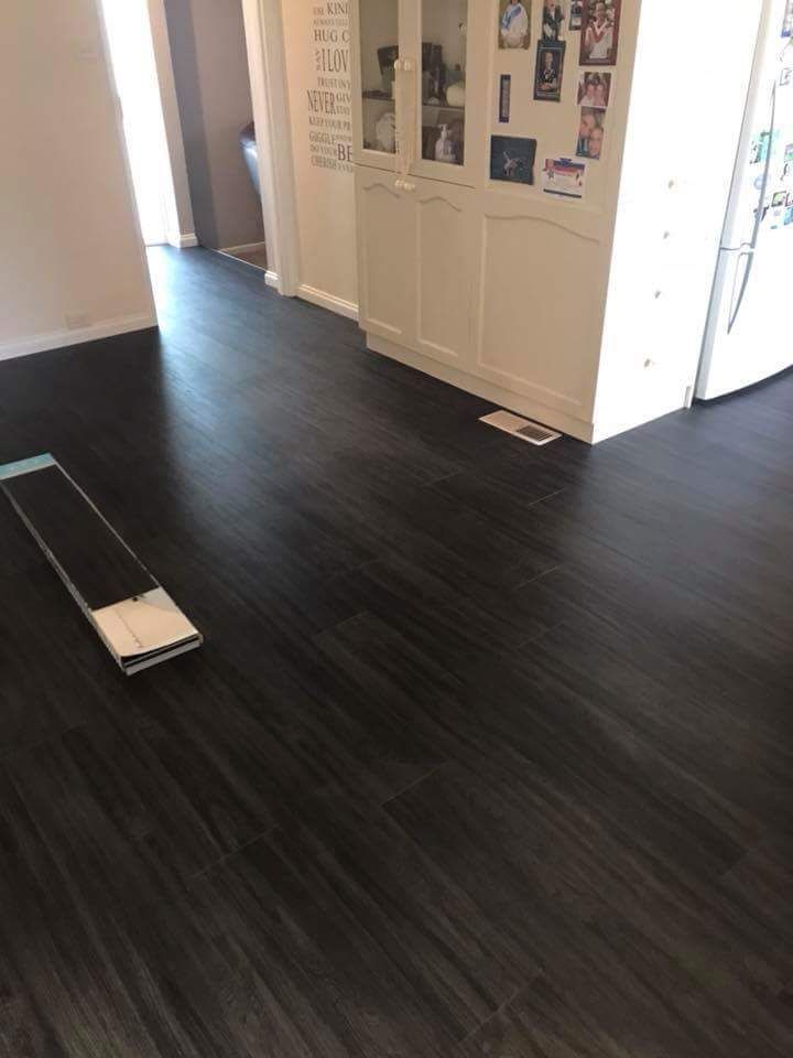 A Black Wooden Floor Is Being Installed In A Kitchen — Queanbeyan Carpets in Queanbeyan, NSW