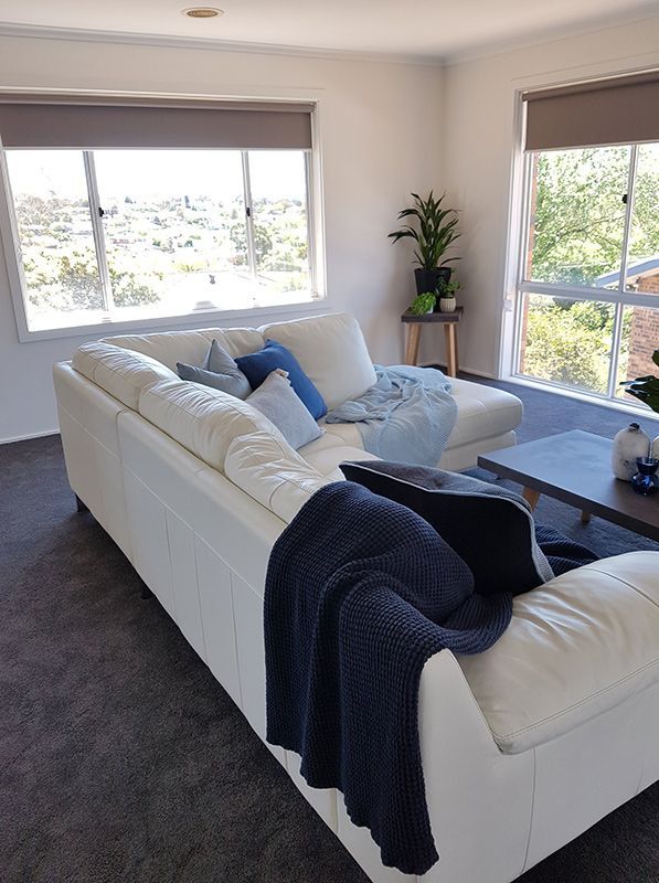 A Living Room With A White Couch, Black Carpet, And A Blue Blanket On It — Queanbeyan Carpets in Queanbeyan, NSW