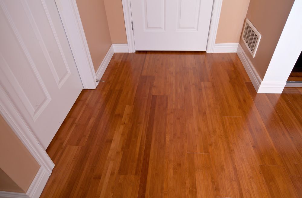 Empty Hallway With Glossy Hardwood Floor, White Doors, and Tan Walls — Queanbeyan Carpets in Queanbeyan, NSW