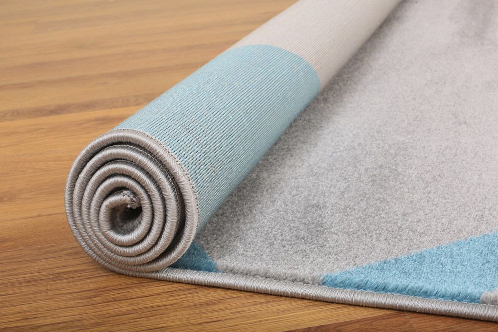 A Man Is Rolling A Roll Of Carpet On The Floor — Queanbeyan Carpets in Queanbeyan, NSW