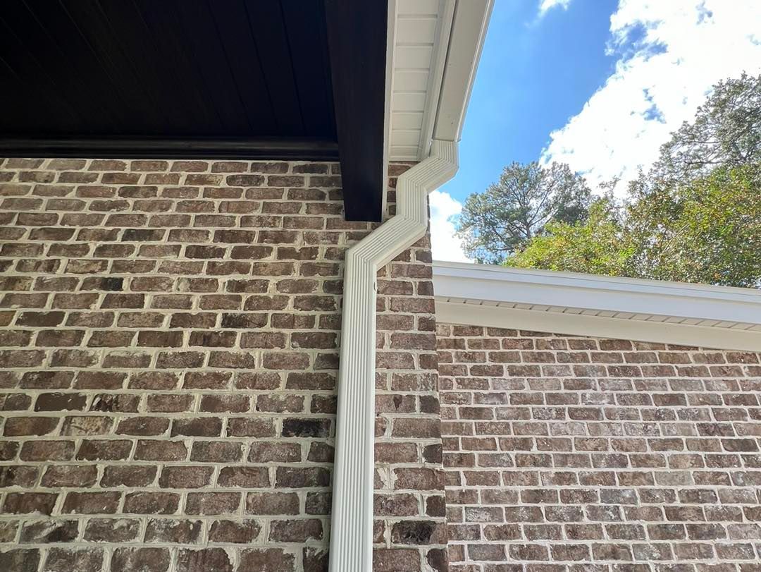 A close up of a brick wall with a white gutter on it.