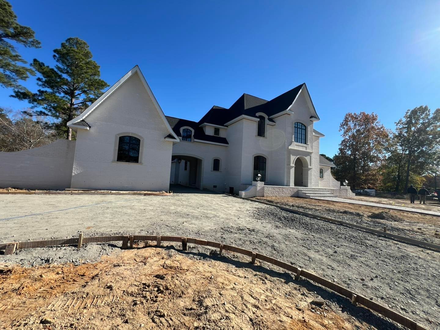 A large white house with a black roof is being built.