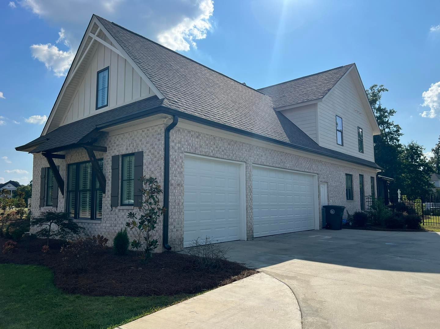 A large white house with two garage doors and a driveway.