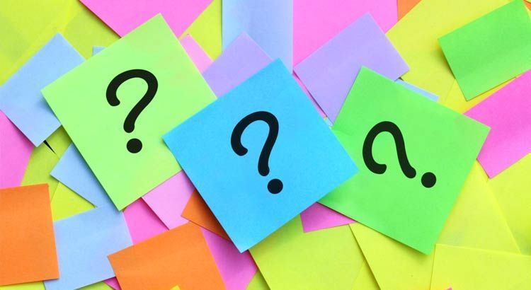 Question marks on colorful sticky notes, scattered on a table.
