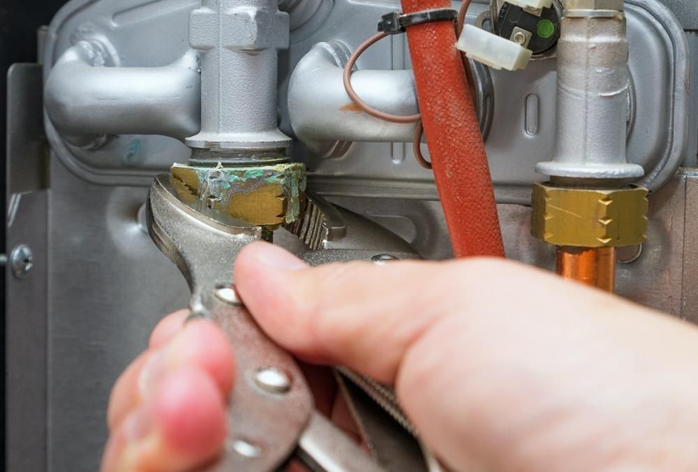 Hand Using Pliers to Tighten a Nut on A Silver and Bronze-Colored Plumbing Fixture — Joy Hire Compressor Hire & Maintenance in Paget, QLD