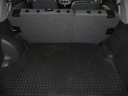 The trunk of a car with a black mat on the floor.