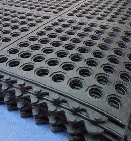 A close up of a stack of black rubber mats with holes in them.