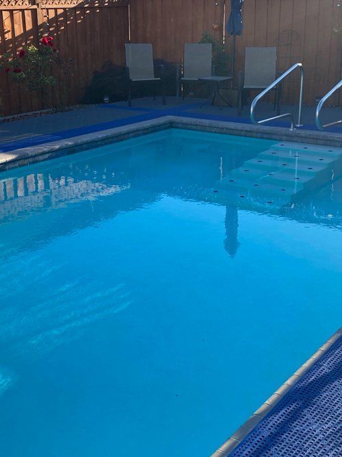 A large swimming pool surrounded by chairs and a wooden fence.