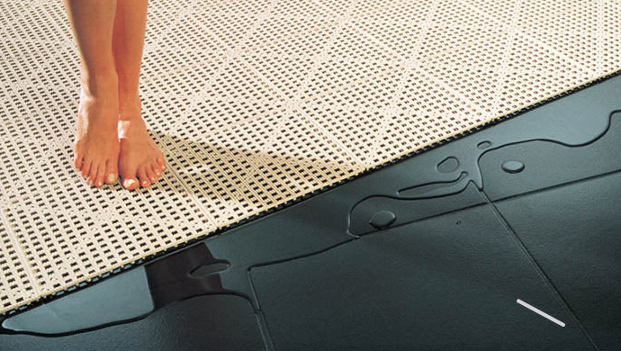A person 's feet are standing on a rug on the floor.