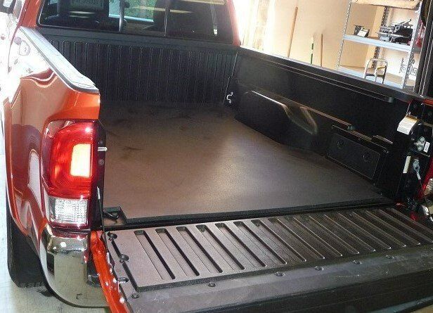 A red truck is parked in a garage with the bed open