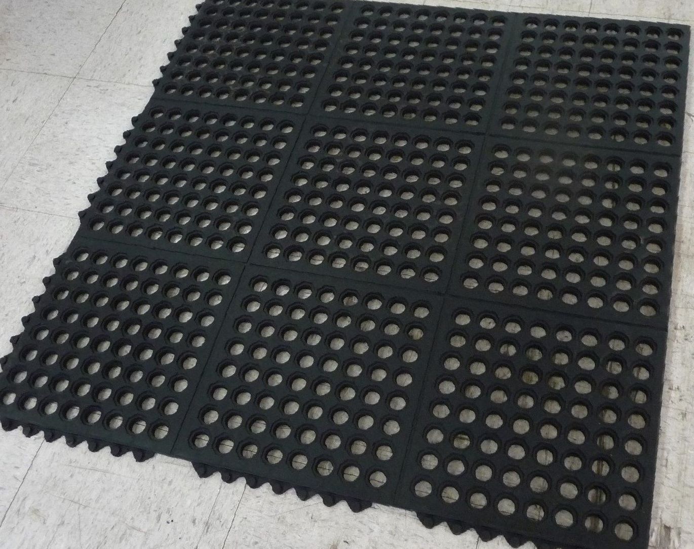 A black mat with holes in it is laying on the floor