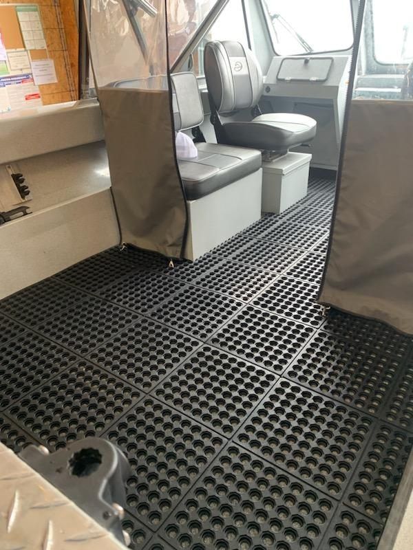 The inside of a boat with a rubber floor and seats.