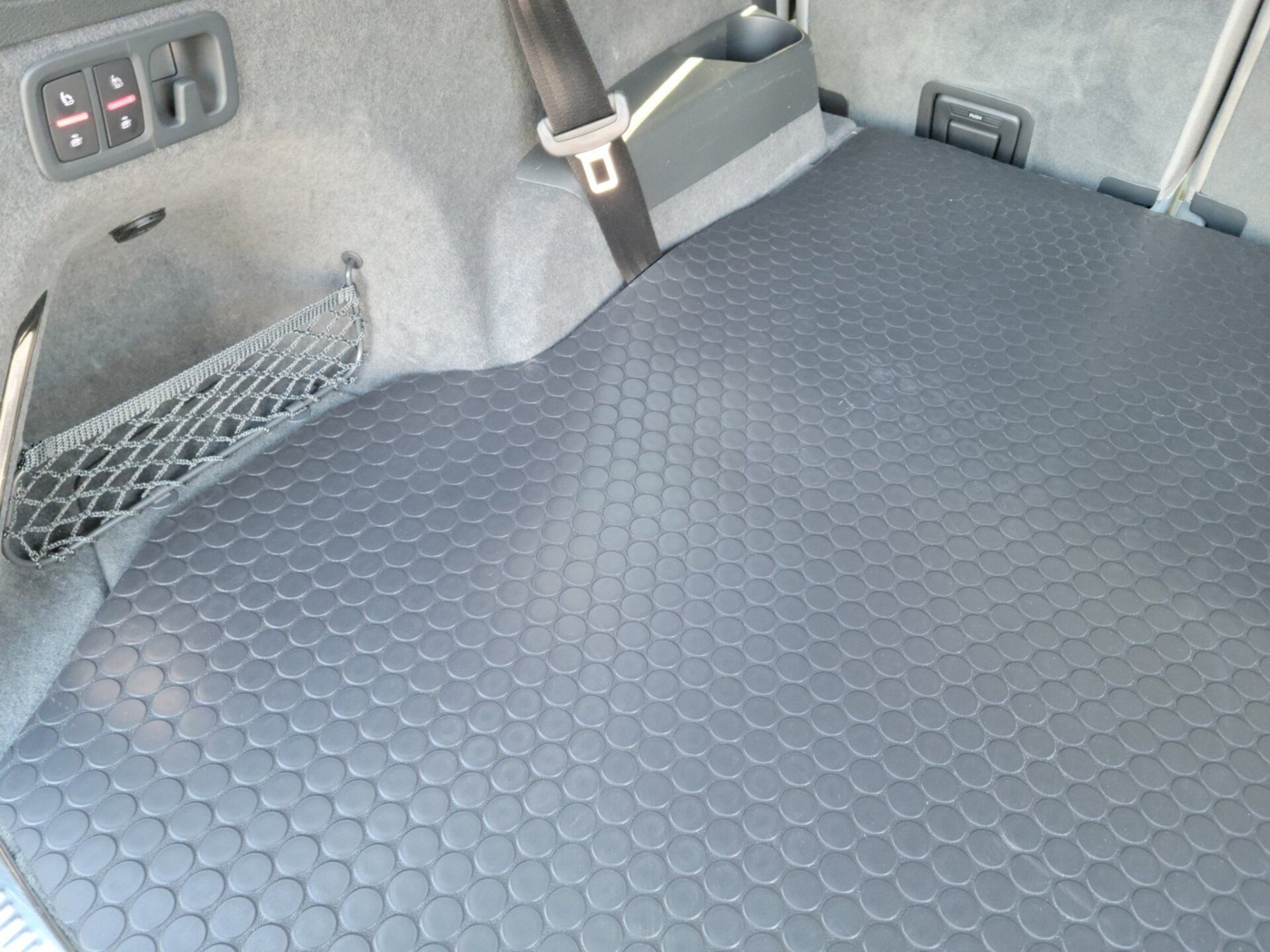 The trunk of a car has a black mat on it