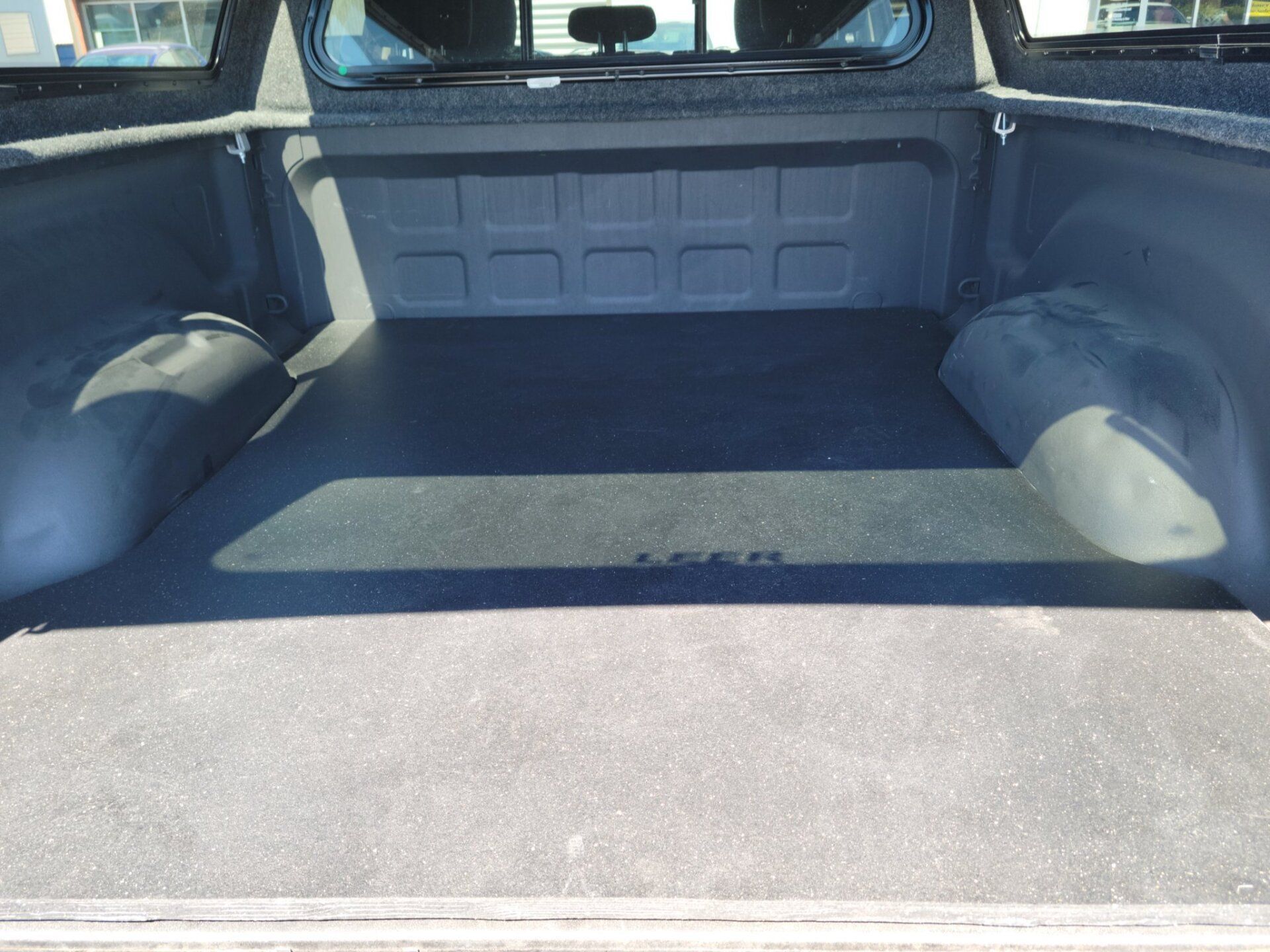 The trunk of a truck is empty and has a carpeted floor.