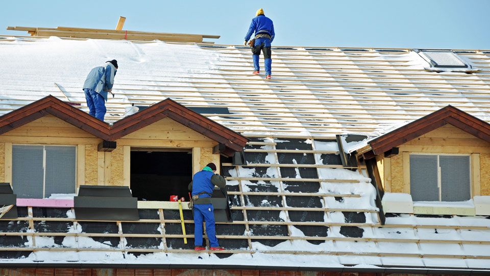 Dachdecker beim Dachdecken im Winter