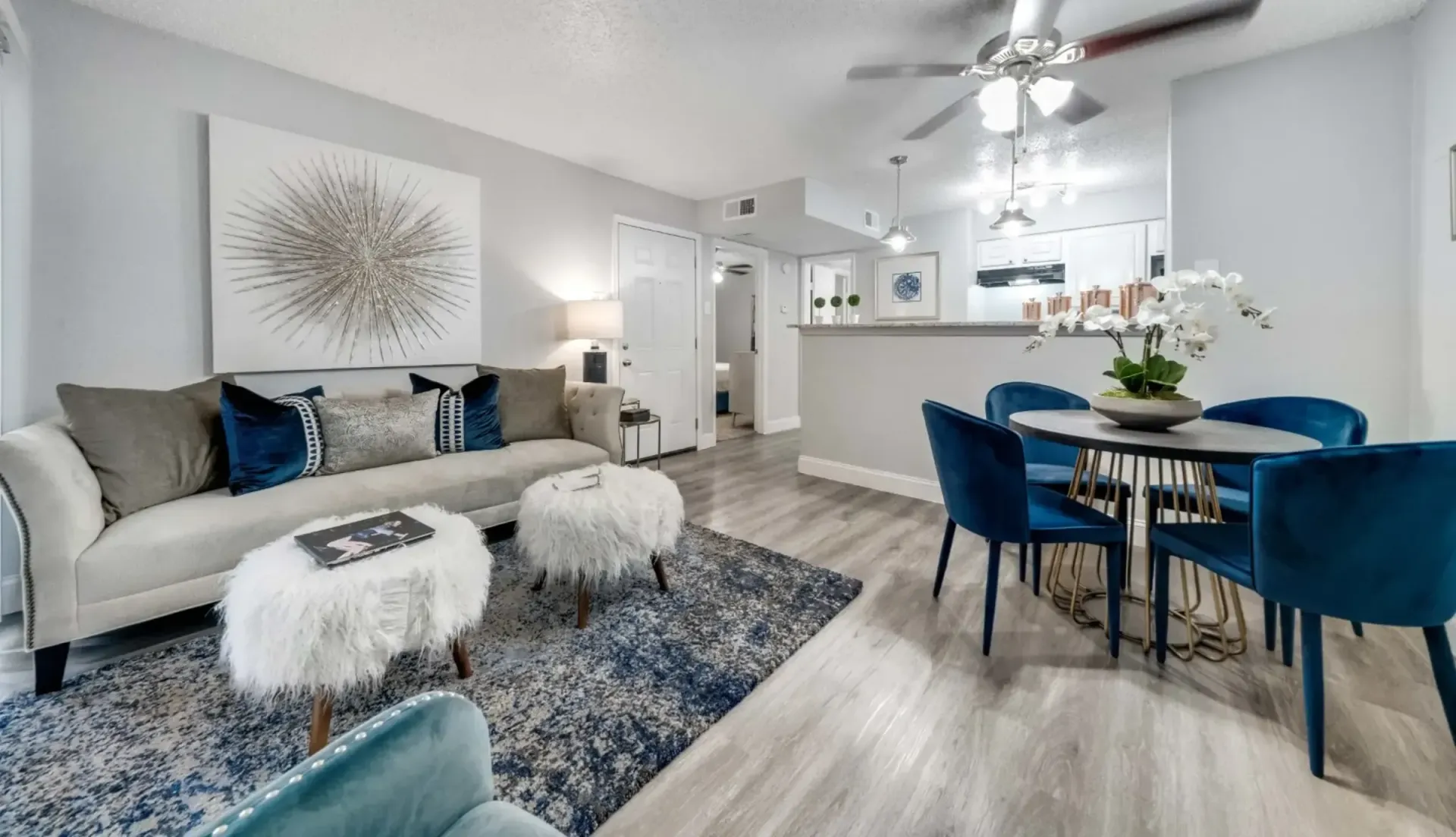 A living room with a couch , chairs , a table and a ceiling fan.