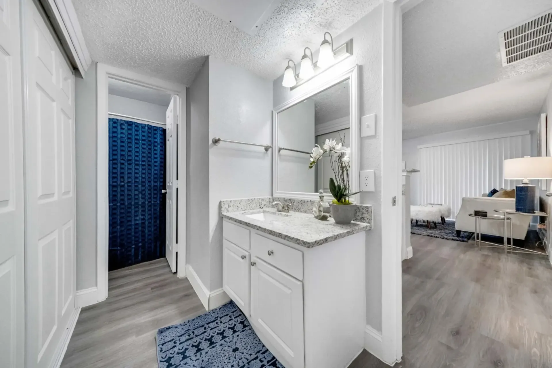 A bathroom with a sink , mirror , and blue curtain.